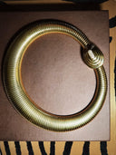 Gold snake-shaped object on a brown surface with a zebra print background